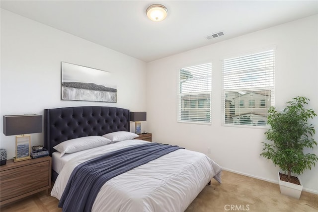 bedroom with light carpet, visible vents, and baseboards