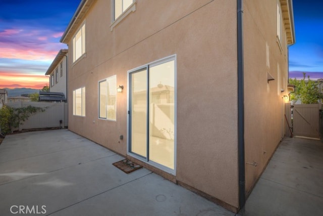 property exterior at dusk featuring a patio area