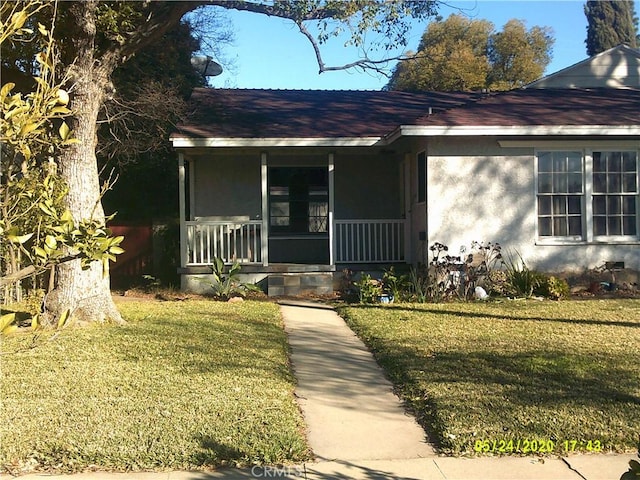 doorway to property with a porch and a lawn