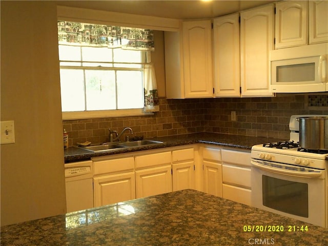 kitchen with sink, white appliances, tasteful backsplash, white cabinets, and dark stone counters