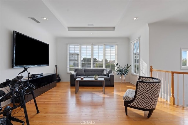 living room with a tray ceiling and light wood-type flooring