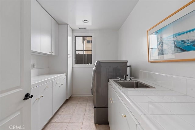 washroom featuring cabinets, washer / clothes dryer, sink, and light tile patterned floors