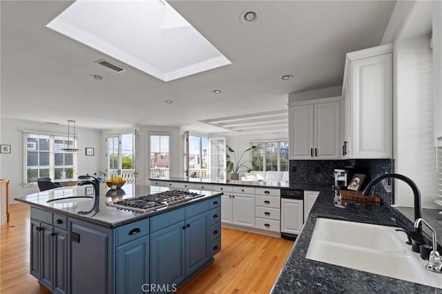 kitchen with sink, stainless steel gas cooktop, white cabinets, and a kitchen island