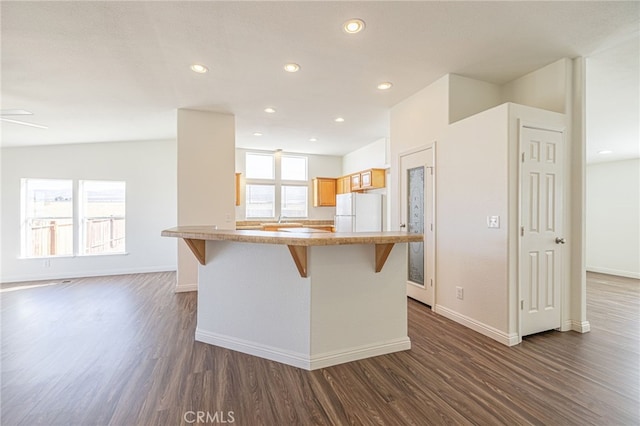 kitchen with dark hardwood / wood-style flooring, a breakfast bar area, a healthy amount of sunlight, and white refrigerator