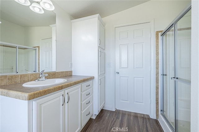 bathroom with walk in shower, vanity, and hardwood / wood-style floors