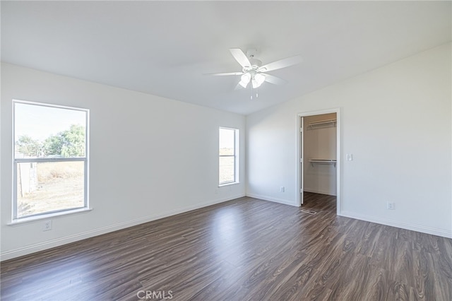 unfurnished bedroom featuring vaulted ceiling, dark hardwood / wood-style floors, a spacious closet, ceiling fan, and a closet