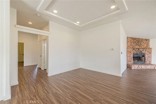 unfurnished living room with a raised ceiling, a fireplace, and dark hardwood / wood-style flooring