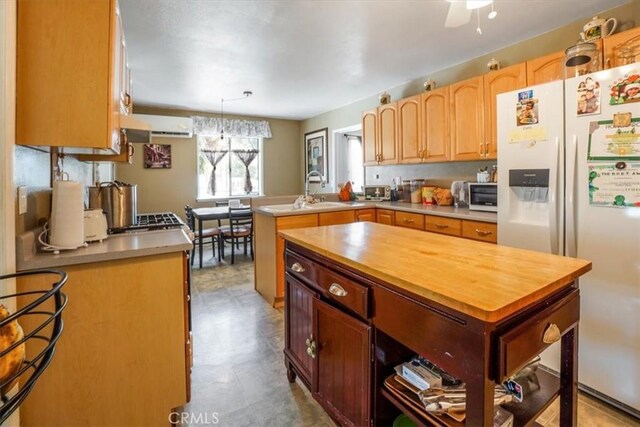 kitchen with sink, hanging light fixtures, white refrigerator with ice dispenser, a center island, and kitchen peninsula