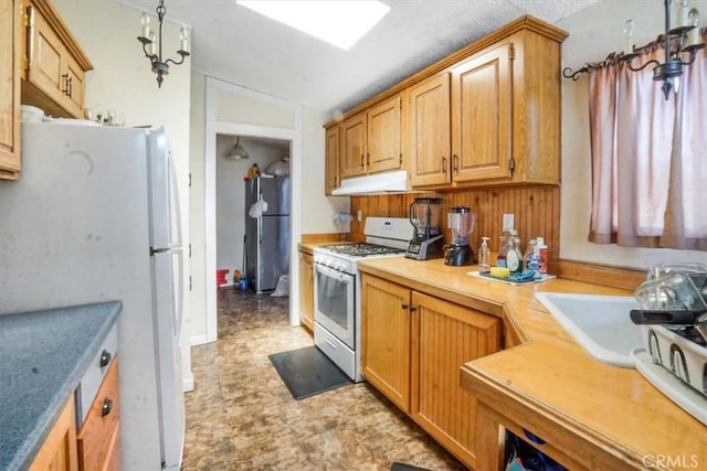 kitchen featuring white appliances, lofted ceiling, and sink