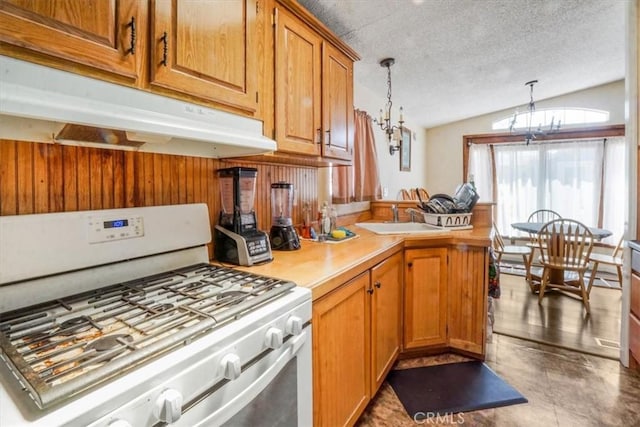 kitchen featuring pendant lighting, lofted ceiling, sink, a notable chandelier, and gas range gas stove