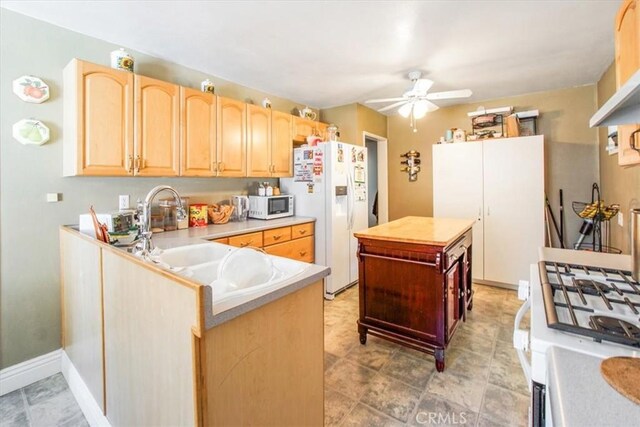 kitchen with sink, ceiling fan, kitchen peninsula, light brown cabinets, and white appliances