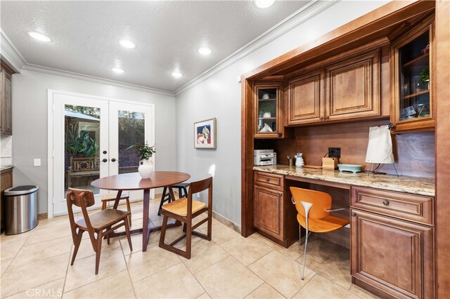 tiled dining area with ornamental molding, built in desk, a textured ceiling, and french doors