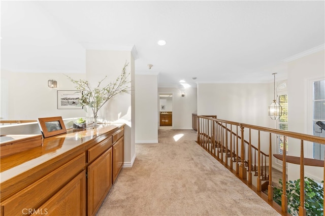 hall featuring crown molding, light colored carpet, and an inviting chandelier