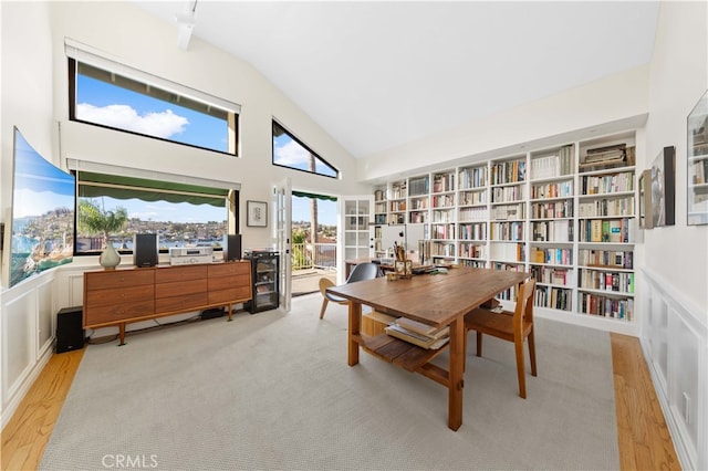 home office with built in shelves, high vaulted ceiling, and light hardwood / wood-style floors