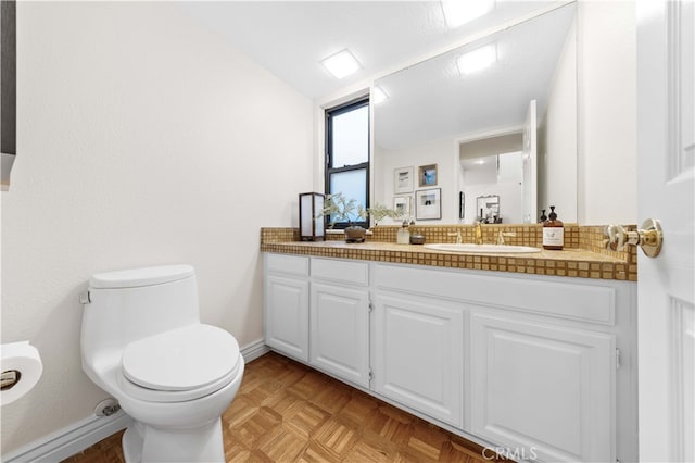 bathroom with parquet flooring, vanity, and toilet