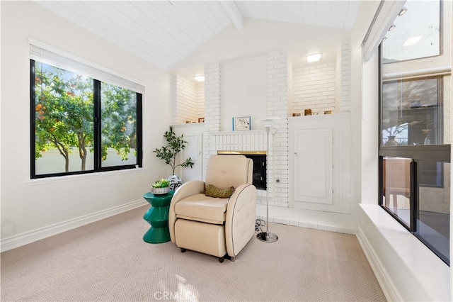 sitting room with lofted ceiling with beams, a brick fireplace, and carpet floors