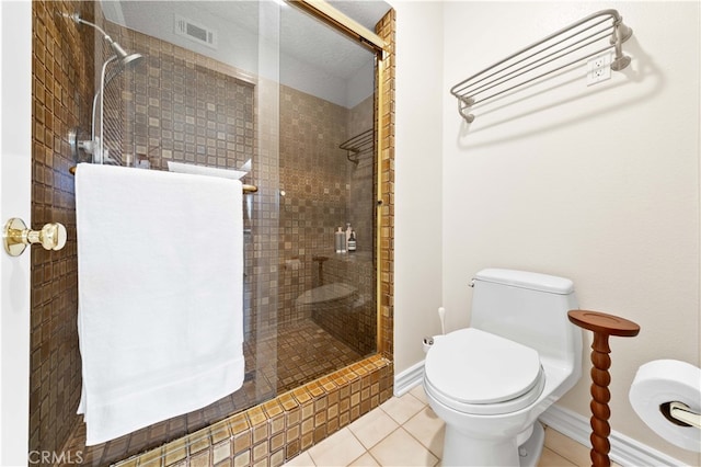 bathroom featuring tiled shower, toilet, and tile patterned flooring