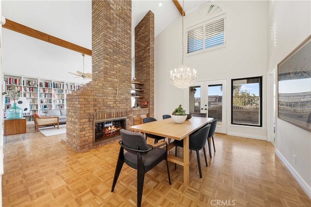 dining area featuring a brick fireplace, a towering ceiling, ceiling fan with notable chandelier, and light parquet floors