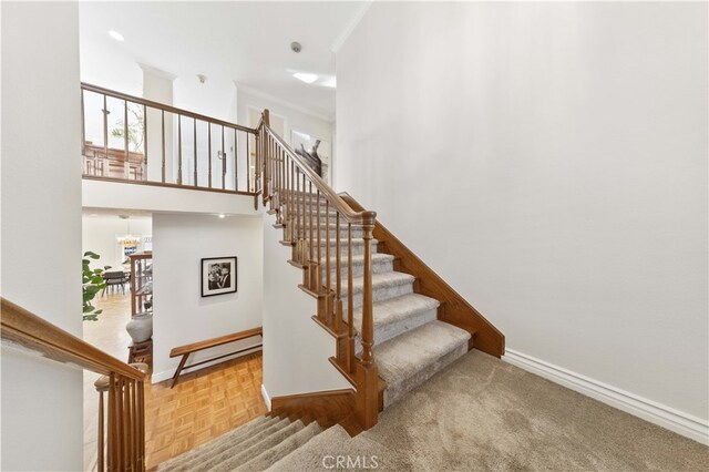 stairway featuring parquet floors, a notable chandelier, and a high ceiling