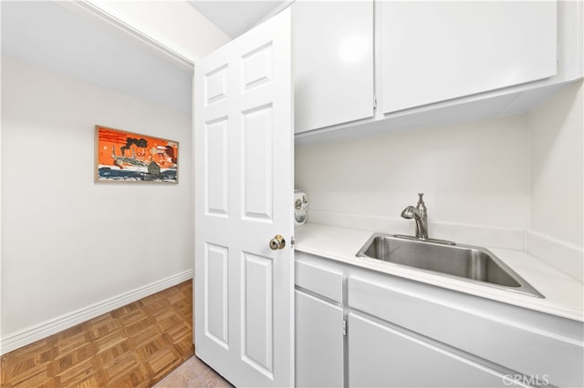 kitchen with light parquet floors, sink, and white cabinets