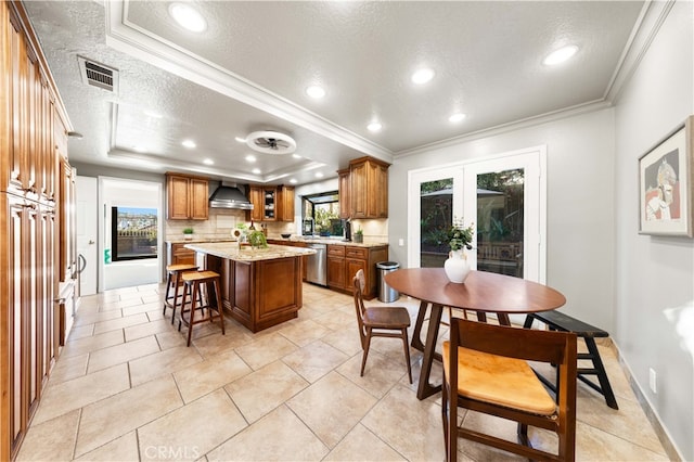 kitchen featuring crown molding, dishwasher, a tray ceiling, a kitchen island, and wall chimney exhaust hood