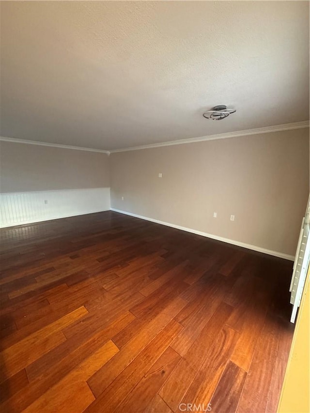 spare room with crown molding and dark wood-type flooring