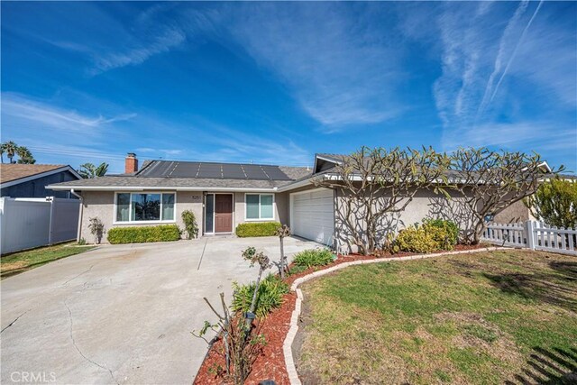 single story home with a garage, a front yard, and solar panels