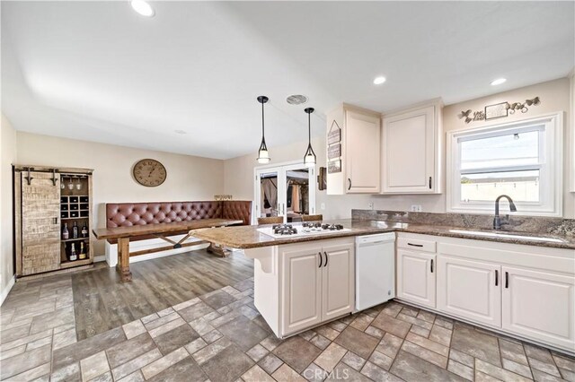 kitchen featuring sink, white cabinets, hanging light fixtures, kitchen peninsula, and white appliances