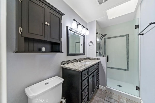 bathroom featuring a skylight, vanity, toilet, and an enclosed shower