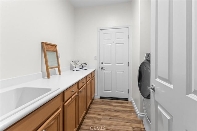 laundry room featuring sink, washer / dryer, cabinets, and hardwood / wood-style flooring