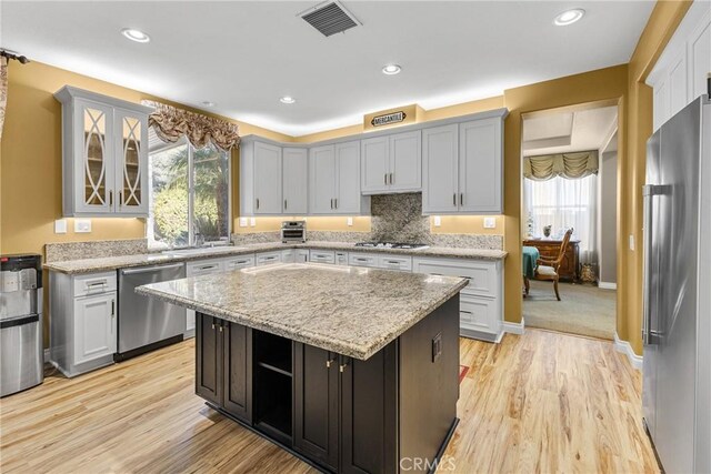 kitchen featuring stainless steel appliances, light hardwood / wood-style floors, a healthy amount of sunlight, and a kitchen island