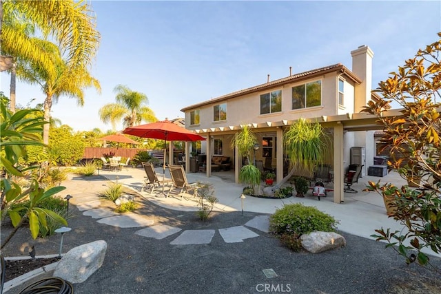 back of property with stucco siding, a chimney, a patio, and fence