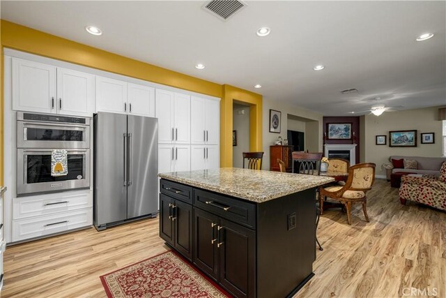 kitchen with light hardwood / wood-style flooring, stainless steel appliances, white cabinets, and a kitchen island