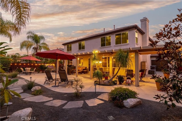 back house at dusk with a patio area