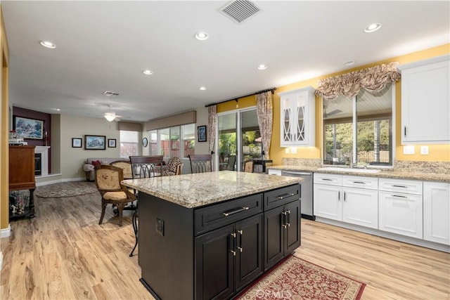 kitchen featuring sink, dishwasher, a center island, white cabinets, and light wood-type flooring