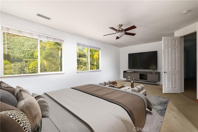 carpeted bedroom with a ceiling fan and visible vents