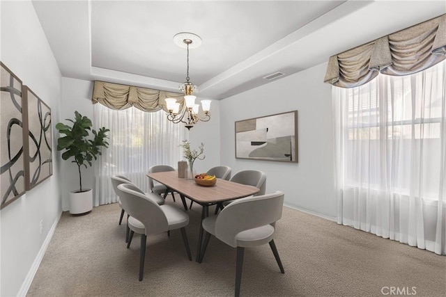 dining area featuring visible vents, a tray ceiling, an inviting chandelier, baseboards, and light colored carpet