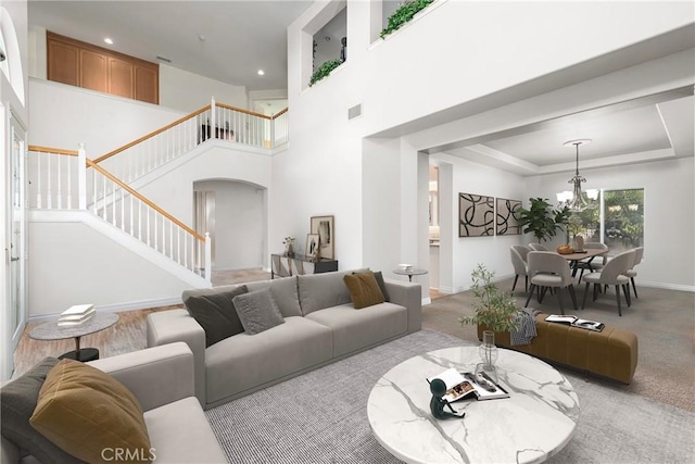 living room with baseboards, visible vents, stairs, a towering ceiling, and a chandelier