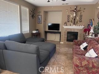 living room featuring ceiling fan and a tile fireplace