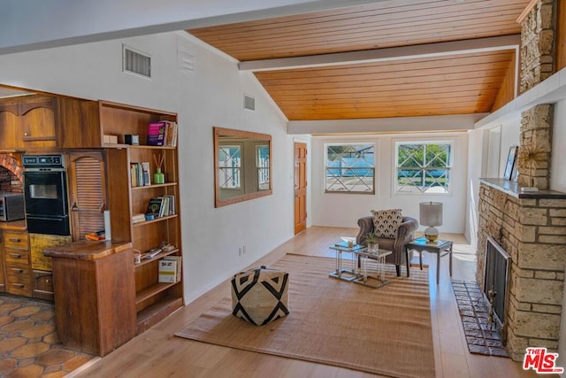 living room with a stone fireplace, light hardwood / wood-style flooring, lofted ceiling with beams, and wooden ceiling