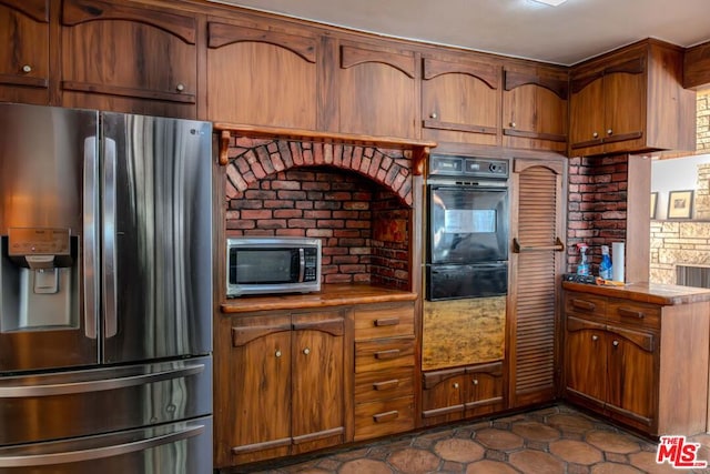 kitchen featuring brick wall, stainless steel appliances, and tile counters