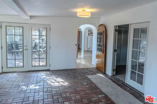 interior space featuring beam ceiling, a textured ceiling, and french doors