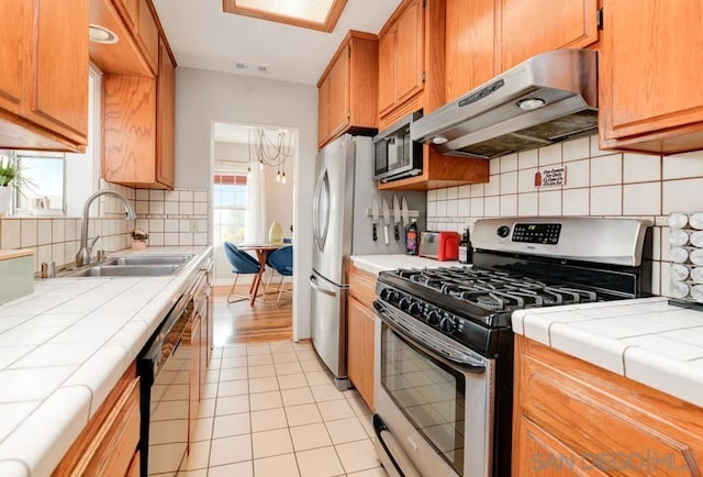 kitchen with sink, light tile patterned floors, backsplash, stainless steel appliances, and tile countertops