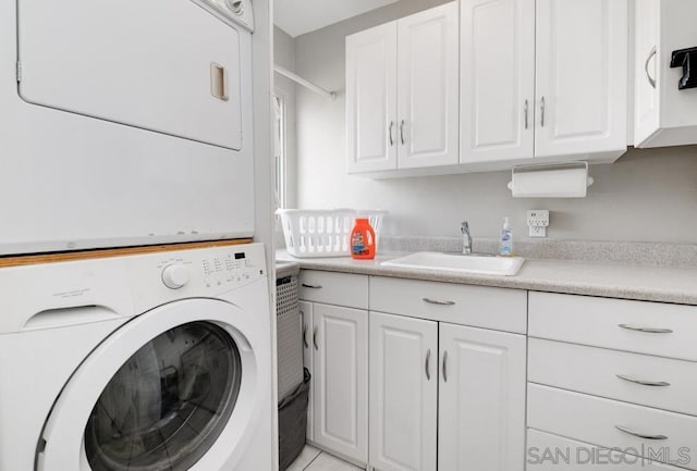 laundry area with light tile patterned flooring, cabinets, stacked washer and clothes dryer, and sink