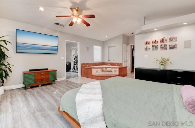 bedroom featuring lofted ceiling, a walk in closet, light wood-type flooring, a closet, and ceiling fan