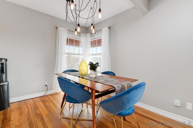 dining space featuring beamed ceiling, hardwood / wood-style floors, and a notable chandelier