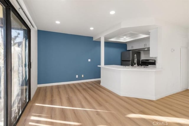 kitchen featuring gray cabinetry, stainless steel fridge, hardwood / wood-style flooring, stove, and kitchen peninsula