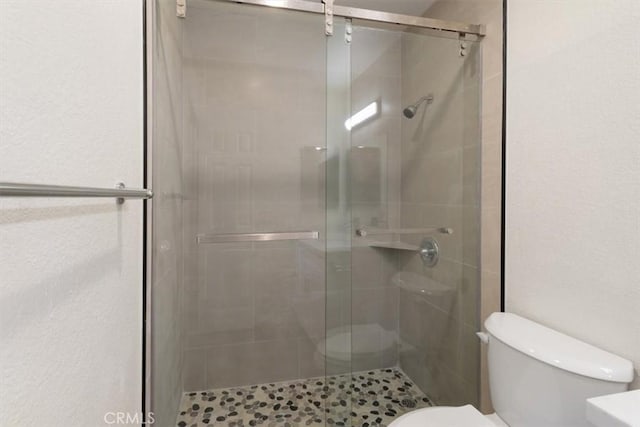 bathroom with a shower with door and toilet