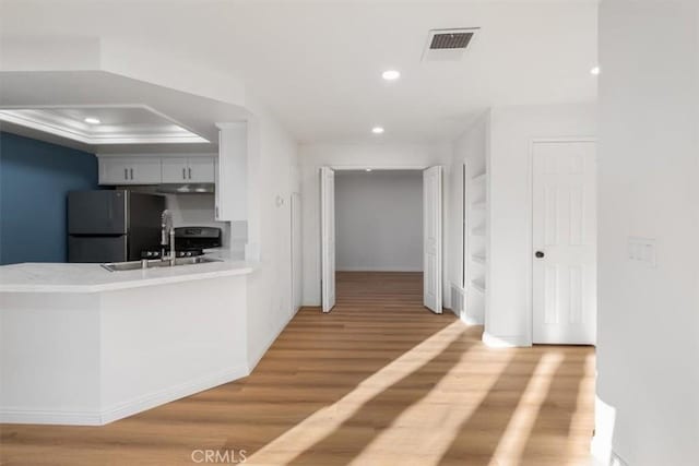 kitchen featuring sink, crown molding, hardwood / wood-style flooring, stainless steel refrigerator, and a raised ceiling