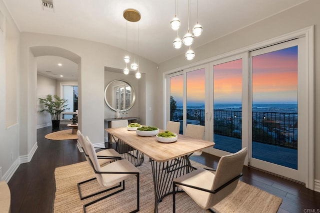 dining area featuring vaulted ceiling, dark hardwood / wood-style floors, and a water view